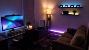 Editorial photo of an affordable spare-room gaming mancave with simple desk, couch, console shelf, diffused accent lighting, storage bins, and abstract monitor glow, no text or logos